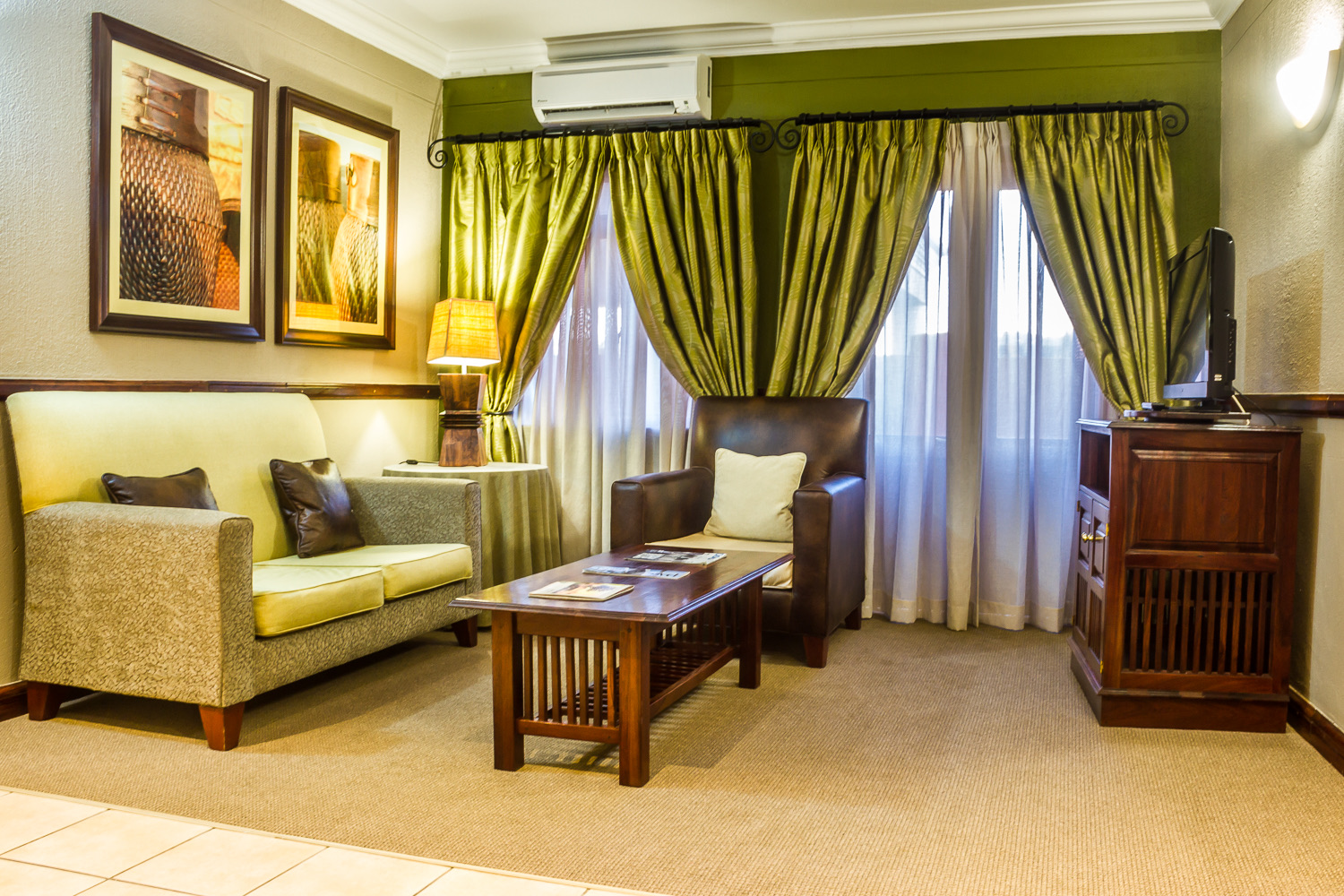 Executive Suite lounge with green curtains and leather armchair at Mondior Gaborone