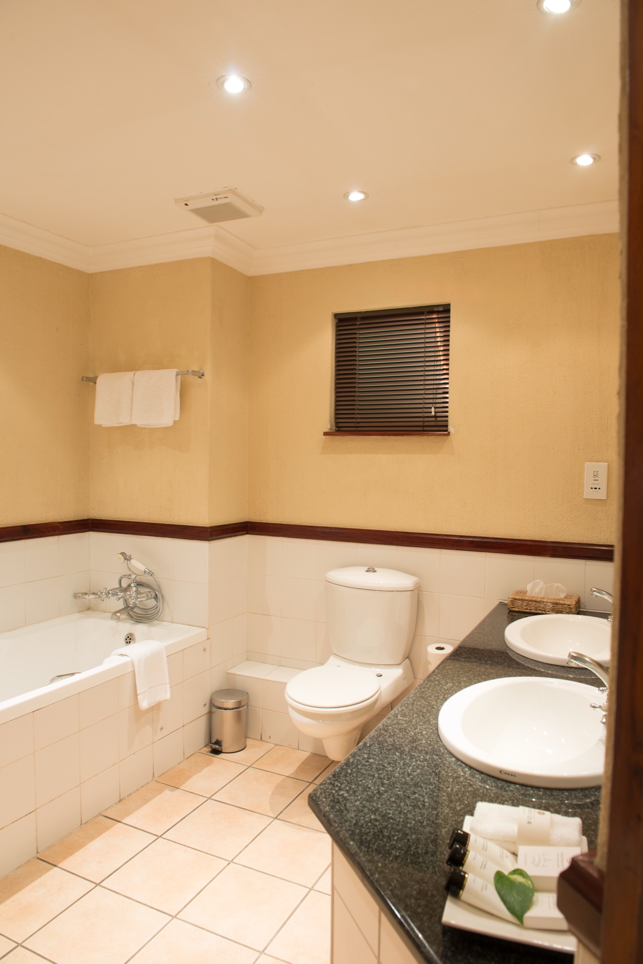 Executive Suite bathroom with twin basins and tub at Mondior Gaborone